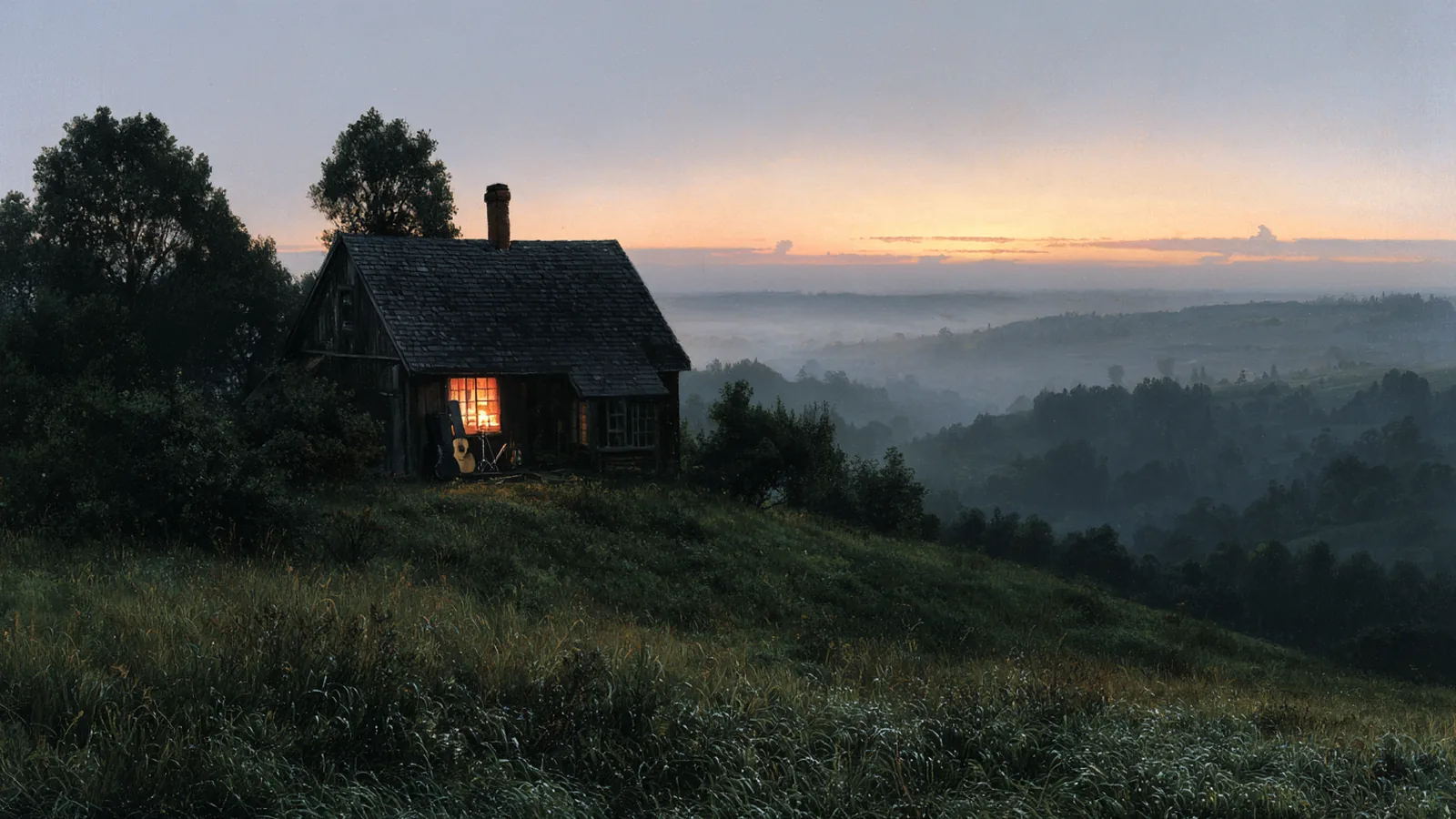 A small wooden cabin with a lit window and a guitar by the door, on a grassy hill at dusk above misty valleys.